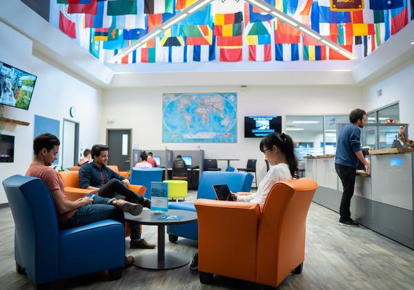 Flags of the world on the wall above students hanging out inside