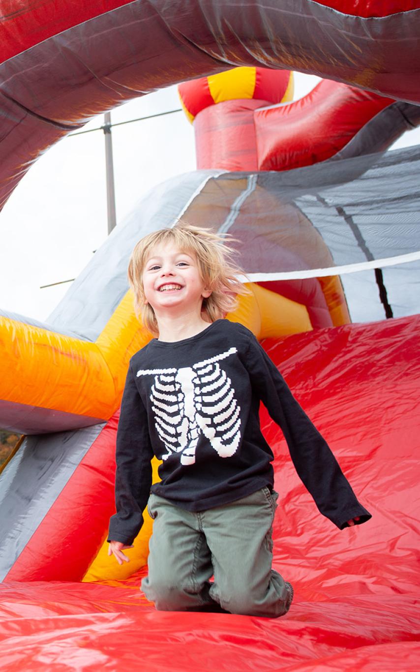 Child in skeleton hoodie having a great time on a bouncy castly